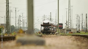 Car transport train loaded with new vehicles at a rail yard, foreground focus on tracks