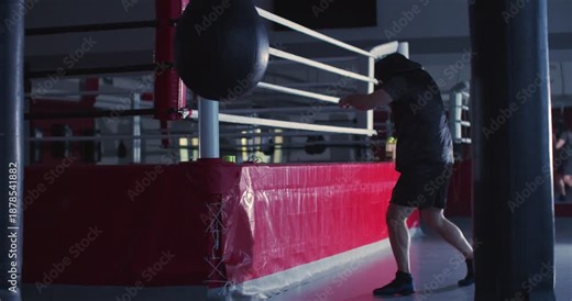 Shadow fighting session shows a man boxer's skill and determination in low light. Man boxer during shadow fighting workout in a dark boxing gym.