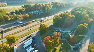 Top view of large rest area near busy multilane American freeway with fast moving cars and trucks. Recreational resting place during interstate traveling