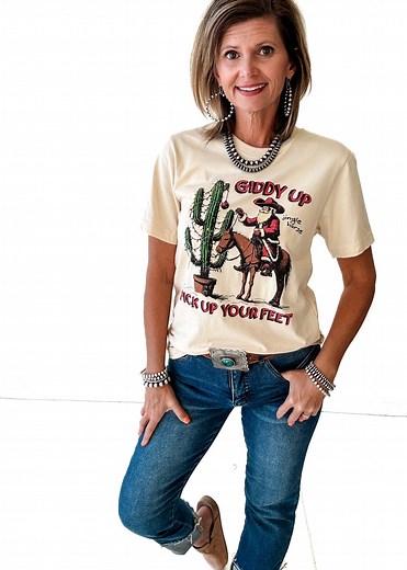 🎅 Saddle up, Santa style! The Giddy Up Tee is the cutest Western twist on Christmas. Featuring a jolly cowboy Santa riding his horse by a cactus tree, it’s perfect for ranch days, tree shopping, or holiday parties with a little yeehaw flair. ✨ Don’t forget there’s a free shipping over $20 code on the app, and it ships fast from Mineral Wells, Texas! Grab yours here ---> https://rollingranchboutique.com/products/giddy-up-tee-small-to-3x Christmas Collection ---> https://rollingranchboutique.com/