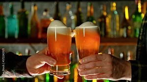 Super slow motion of hitting beer mugs together, cheers concept. Filmed on high speed cinema camera, 1000 fps. Bar with bottles on background. Speed ramp effect.