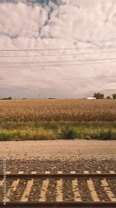 Traveling by Train Through the Countryside. Passenger point of view as a train moves through the rural countryside. Views of farm land and corn crops.