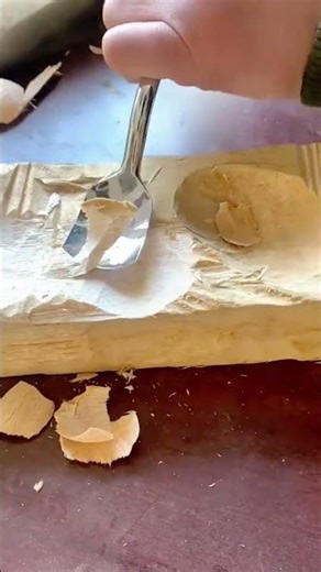 using curved metal gouge to carve out deep circular indentations in block of wood for handcrafting