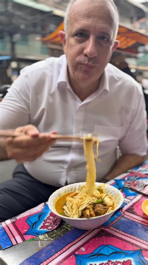 Num Banh Chok Somlar Cary; house 09 Street 109, Near Phsar Dumex, Phnom Penh Since 1981, the same woman has stood behind this counter, ladle in hand, serving bowls of num banh chok somlar cary with the calm precision that only decades of repetition can teach. The place is small, tiled walls, plastic stools, and the faint hum of fans, yet every detail works. Her curry is slow-cooked with chicken, turmeric, lemongrass, and coconut cream until the broth turns golden and the meat softens just enough