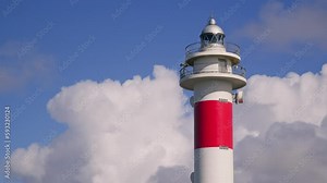 Lighthouse against the background of fast-moving white clouds
