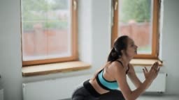 Young fit brunette girl with pigtail in blue top, gray leggings does...