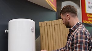 Plumber chooses a boiler in a hardware plumbing store