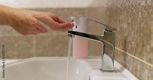 Woman washes her hands thoroughly using liquid soap in bathroom at home