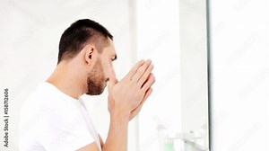 man applying after shave oil to face at bathroom