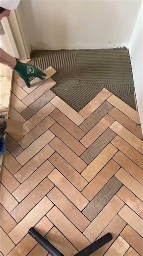 installing brown ceramic tiles in herringbone pattern