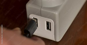 Hand plugging in a USB Type A cord into an adapter or hub - close up