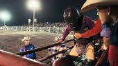 A Bull Rider Wearing a Protective Helmet Prepares to Sit on a Bull in...