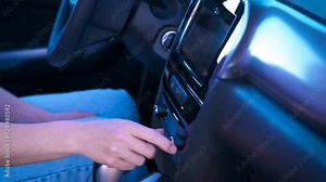 Driver sitting and touch auto button. A female driver press the car buttons on the dashboard. A concept of controlling driver.