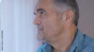 The old man looking out the window. The old man looks out the window.