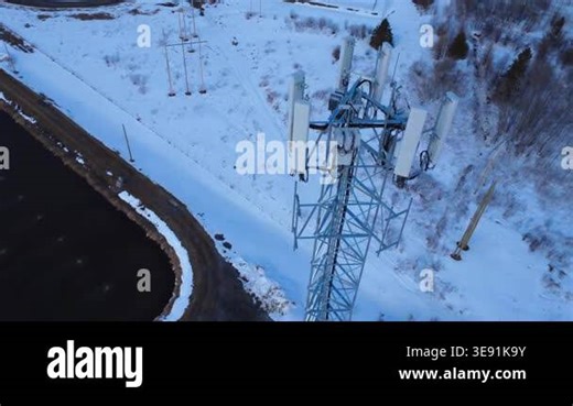 Aerial winter drone footage of a cellular tower beside snowy wastewater ponds, showcasing remote infrastructure, communication networks, and coldseason industrial operations Stock Video Footage - Alamy