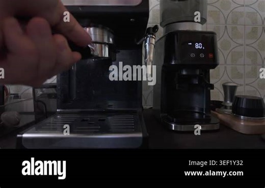 Professional barista preparing a hot beverage by pouring steaming water from an espresso machine into a clear double-walled glass cup, showcasing a daily routine in a kitchen or cafe setting Stock Video Footage - Alamy