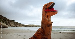 Boxing, comic and dinosaur costume on beach with martial arts or fighting training for sports. Travel, clouds and inflatable animal t rex mascot outfit for boxer with fitness by ocean or sea.