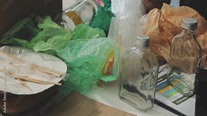 Garbage separation concept. Female hands separate paper and plastic into separate containers in the kitchen at home. Waste segregation, waste sorting, waste recycle.