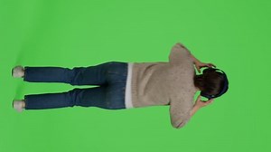 Vertical video: Back view of female person dancing and listening to sounds on headset, having fun with mp3 music and dance moves in studio. Female model enjoying songs on headphones, full body