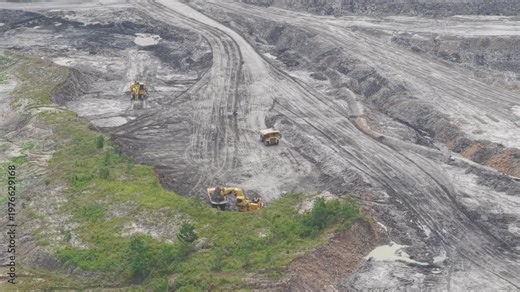 Large excavators dig up the earth and load it into dump trucks, paving the way for hauling in coal mines