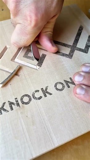 carving wood with a small blade to create geometric patterns and letters with great precision