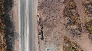 Aerial shot of excavator machine backhoe digging dirt and load filling soil to dump truck at the road construction site
