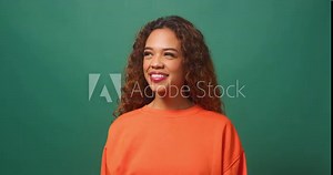 Beautiful young biracial woman wiggles and points one finger up, green studio