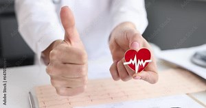 Medical doctor holding red heart icon and showing ok or approval sign. Cardiotherapist doctor conducting heart examination