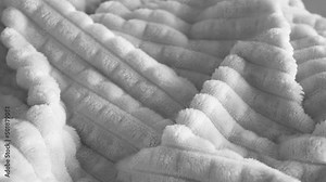 Close-up view 4k stock video footage of fluffy soft textile spinning around slowly. Abstract black and white wavy textured cozy fabric 4k background