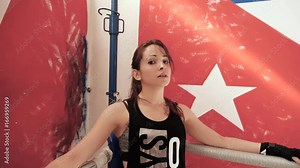 Female boxer leaning on the corner of a boxing ring. Slow motion shot.