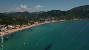 Aerial drone footage capturing the beauty of Agios Georgios beach, with blue turquoise waters and sandy shore, with hills in the backdrop