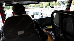 Young fireman controls a big truck riding to the place of fire. Professional fireguard operating the fire car on urban road. Male firefighter driving on fire engine to an emergency. Slow motion