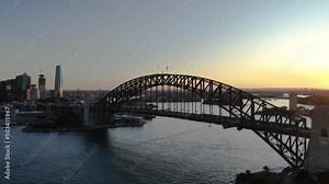 Aerial drone view rising up on Sydney Harbour Bridge turning to view Sydney city in Sydney, NSW during the late afternoon