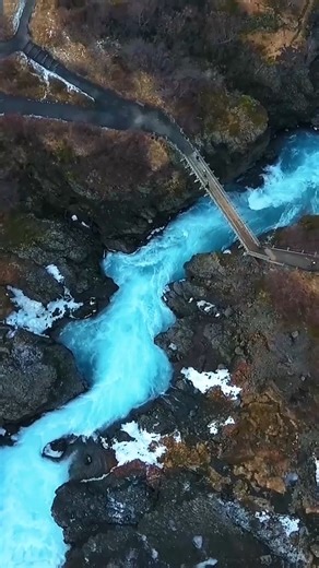 This is what happens when lava meets glacier melt! 🧊 Hraunfossar stretches nearly a kilometer across a hardened lava field, with clear blue water pouring out from cracks in the rock like it’s appearing out of nowhere. No dramatic cliff edge. No thunder. Just endless movement. 🌊💙 It’s calm. But powerful in its own quiet way. | Guide to Iceland