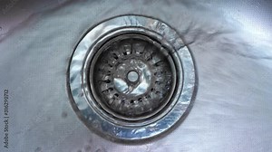 Streaming water in sink. Water stream going down the drain.