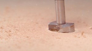 SLOW MOTION TIME WARP, MACRO, DOF: Tiny particles of wood fly into the air as drill bores a hole into the board. Wood chippings fly off the spinning drill boring a wide hole in a piece of timber.