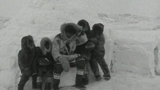 Group of Eskimos gather outside an igloo