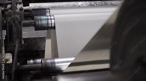 Close up view of a paper running through the printing machine during newspaper printing process in a real time.