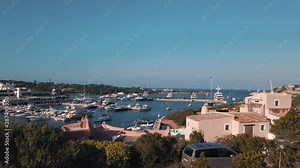 Porto Cervo marina. Northern Sardinia, summer time, day, early evening. Boats, power boats, luxury yachts. Beautiful bay. Blue sky. Pan from left to right from bush. Establishing shot.