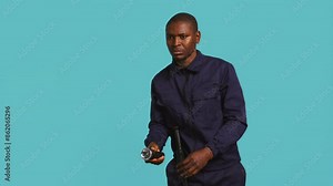 Portrait of security agent securing assigned post, turning on flashlight, studio background. African american guardian prepared to handle security breaches, using lantern device, camera B