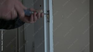 The carpenter installation the lock into the door with a chisel and a hammer