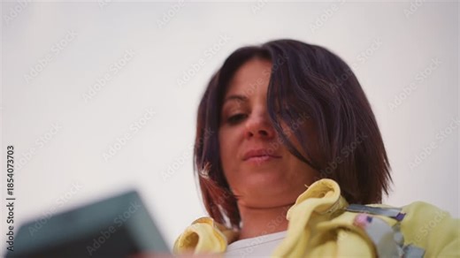 white woman checking product box outdoors, yellow jacket, lowangle perspective, thoughtful expression, hands holding small device, inspecting quality and detail, influencer review vibe, vlog