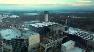 Construction of a modern garbage incineration plant, taking place in the morning, represents sustainable development in a large urban center by generating energy from the burning of municipal waste.