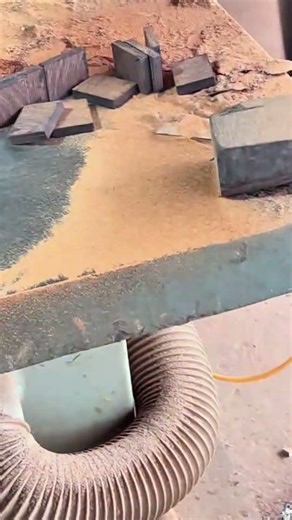 cutting small dark wooden blocks into thin slices using a vertical band saw machine in a workshop
