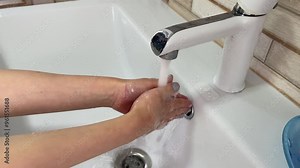 Woman washes her hands with soap and water in a bathroom sink, ensuring proper hygiene and cleanliness