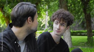 A guy feeds grapes to another guy in the park in the summer. LGBT