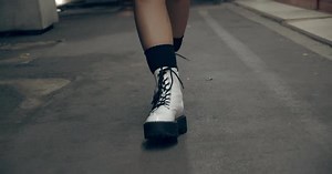 Woman's Feet Taking One Step in Front of Another in White Boots