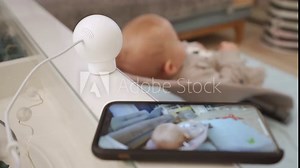 Smart IP camera is installed in the childrens room, indoor security camera works as a baby monitor. Parents watching baby in real-time on smartphone screen. High quality 4k footage