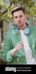 Shh be quiet please. Brunette young man presses index finger to lips makes silence hush gesture sign do not tells gossip secret outdoors. Young guy male stand on urban city street. Town lifestyles