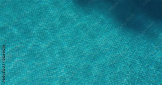 PORTOCOLOM, MALLORCA, SPAIN - OCTOBER, 2025: Turquoise water glistens on a sunny day, pool reflects the sunlight with subtle ripples.